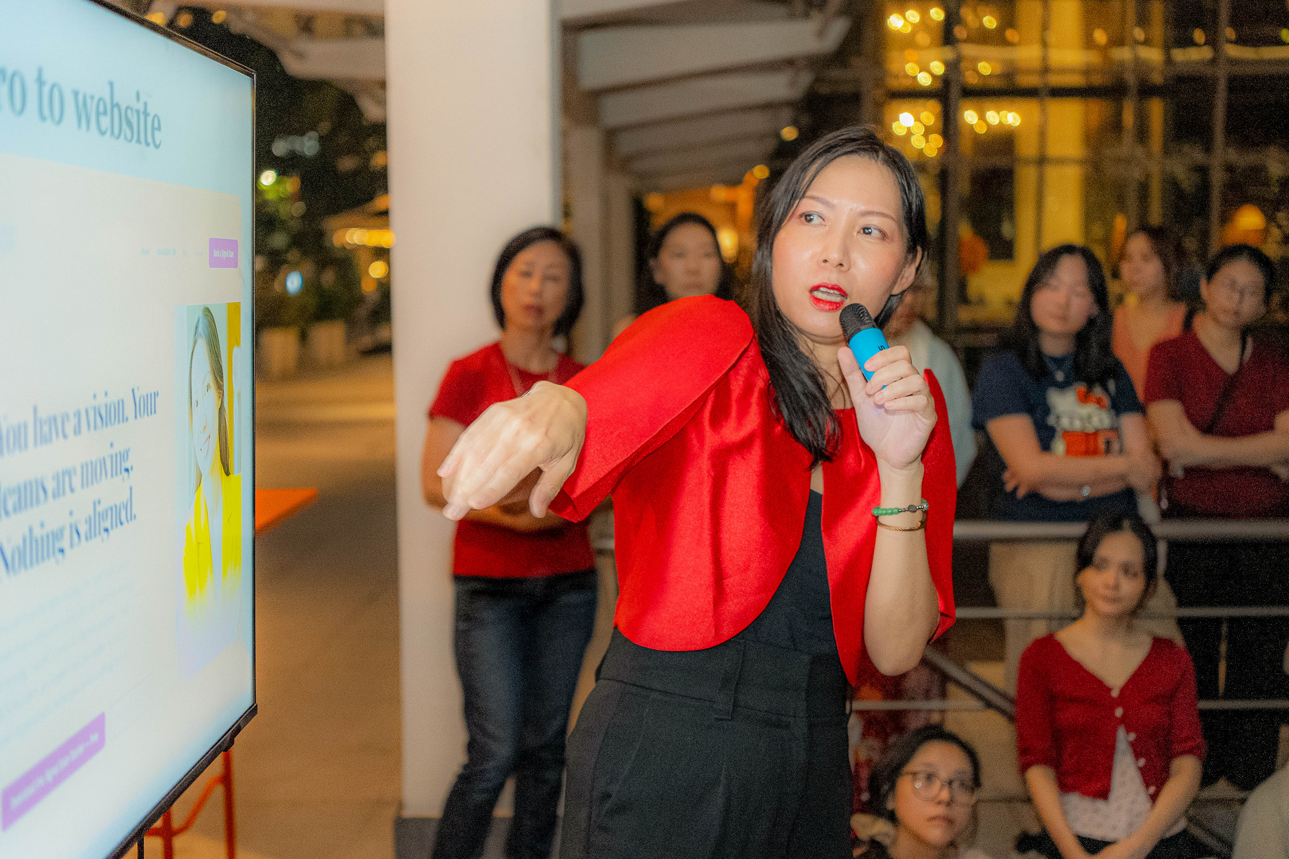 Andrea speaking into the mic, gesturing to her Zero to Website slide