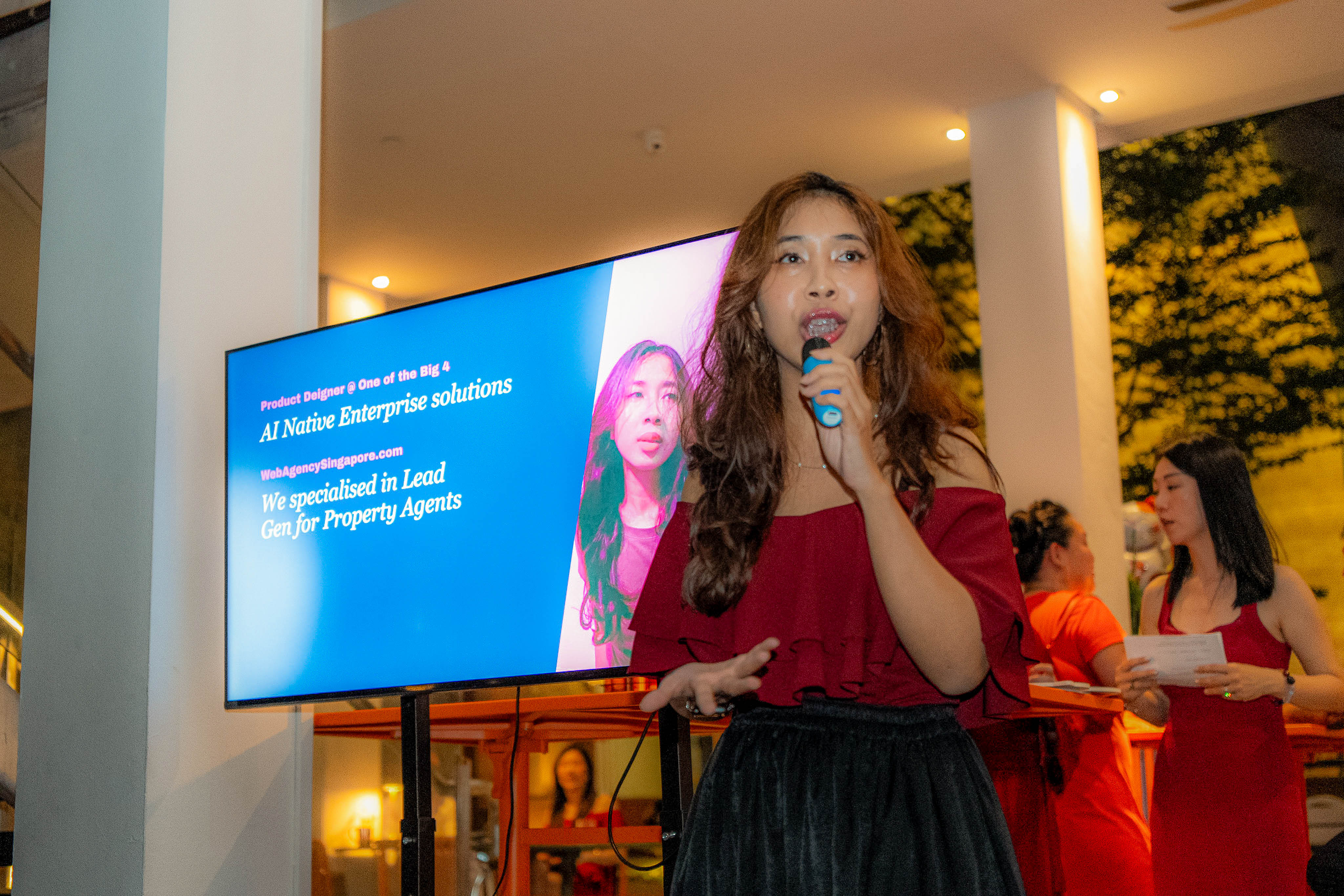 Aya speaking into the mic, with her AI Native Enterprise Solutions slide behind